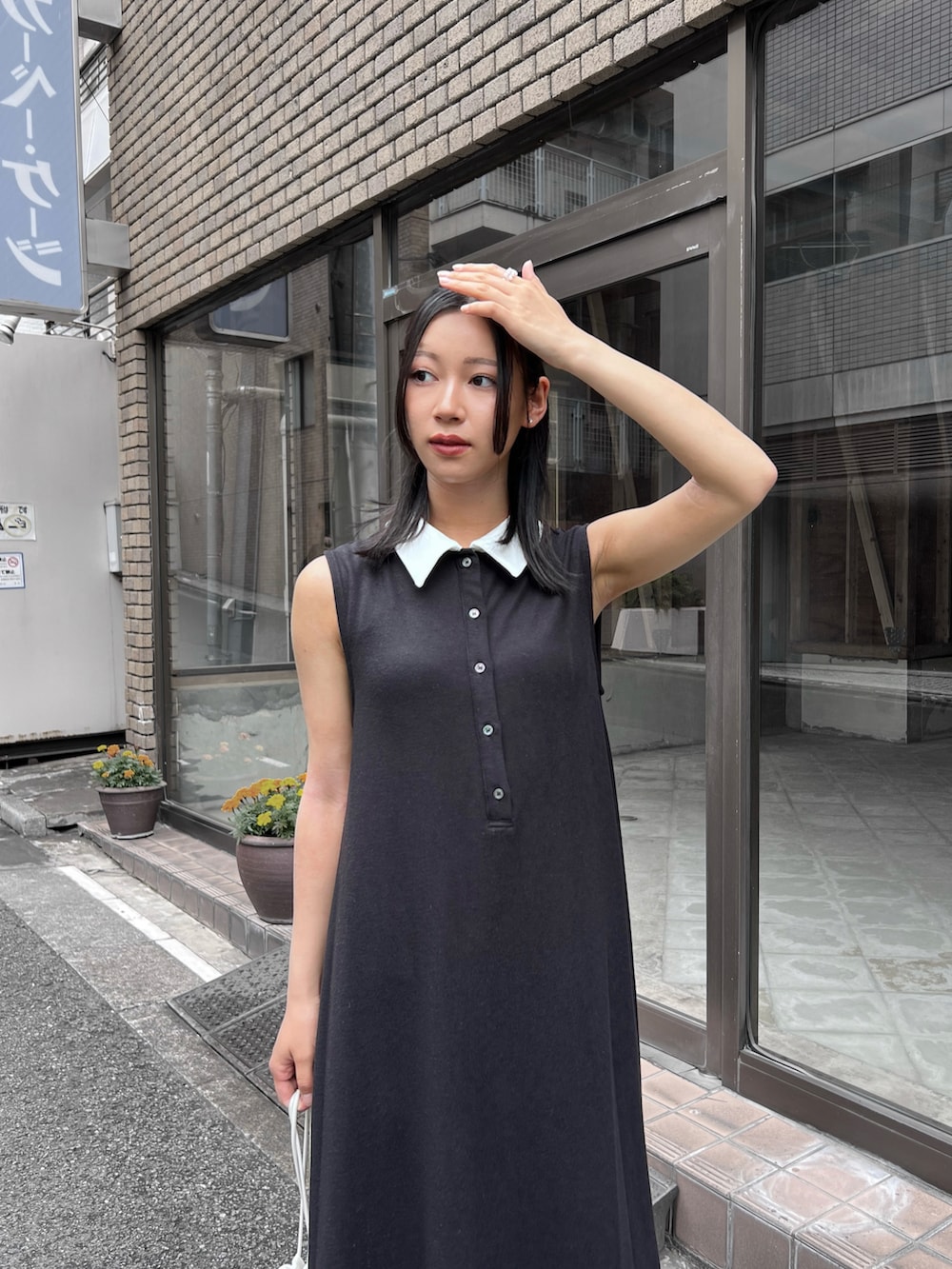 ブラック系のワンピース、ホワイト系のショルダーバッグ、ブラック系のパンプスを着用したレディースの夏コーディネートの2枚目の写真