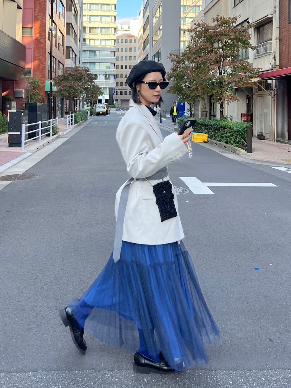 ブラック系のローファー、ブルー系のスカート、ベージュ系のテーラードジャケットを着用したレディースの冬コーディネートの2枚目の写真