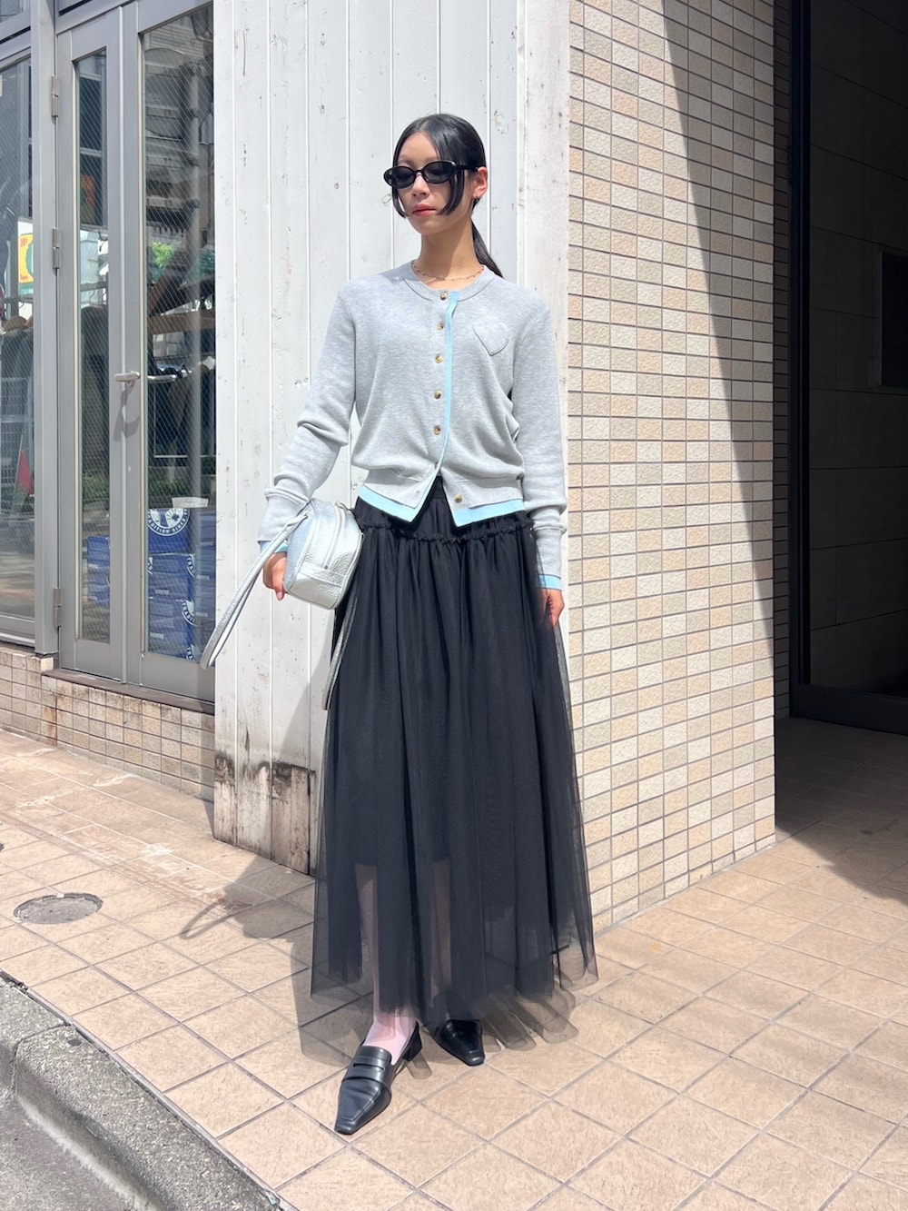 ブラック系のパンプス、グレー系のカーディガン/ボレロ、ブラック系のスカートを着用したレディースの秋コーディネートの2枚目の写真