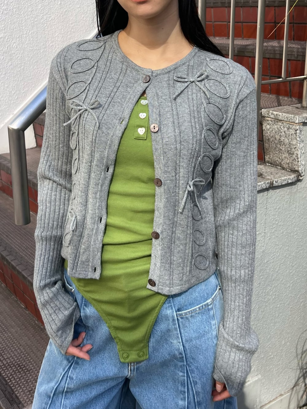 グレー系のカーディガン/ボレロ、グリーン系のキャミソール、ブルー系のデニムパンツを着用したレディースの春コーディネートの3枚目の写真