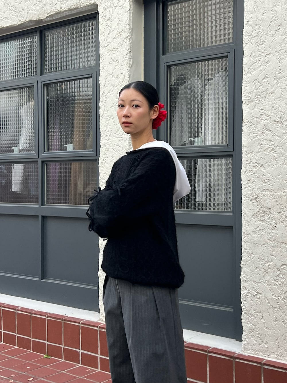 ブラック系のニット/セーター、グレー系のパンツ、レッド系のシュシュを着用したレディースの冬コーディネートの2枚目の写真