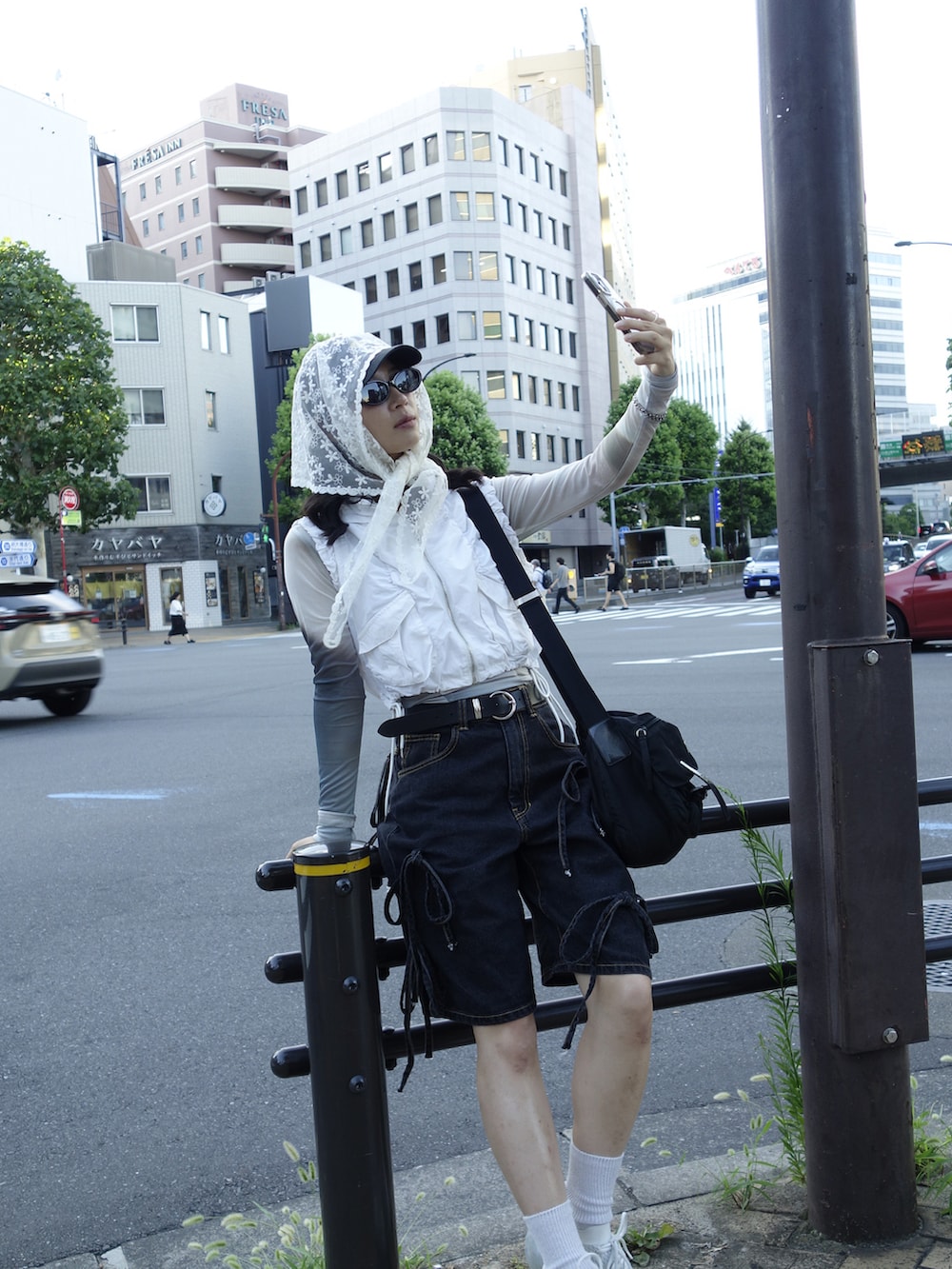 ホワイト系のベスト、ブラック系のデニムパンツ、ホワイト系のスニーカーを着用したレディースの夏コーディネートの4枚目の写真