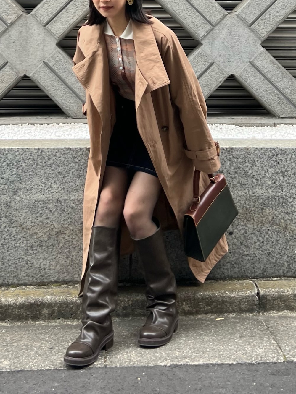 ブラック系のデニムスカート、ブラウン系のブーツを着用したレディースの春コーディネートの3枚目の写真