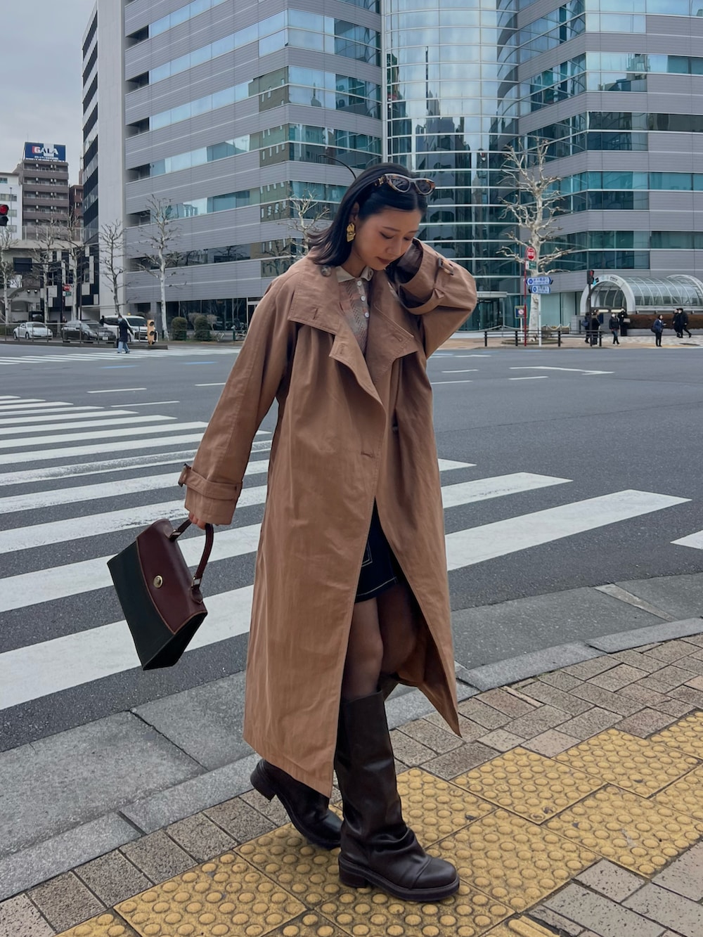 ブラック系のデニムスカート、ブラウン系のブーツを着用したレディースの春コーディネートの2枚目の写真