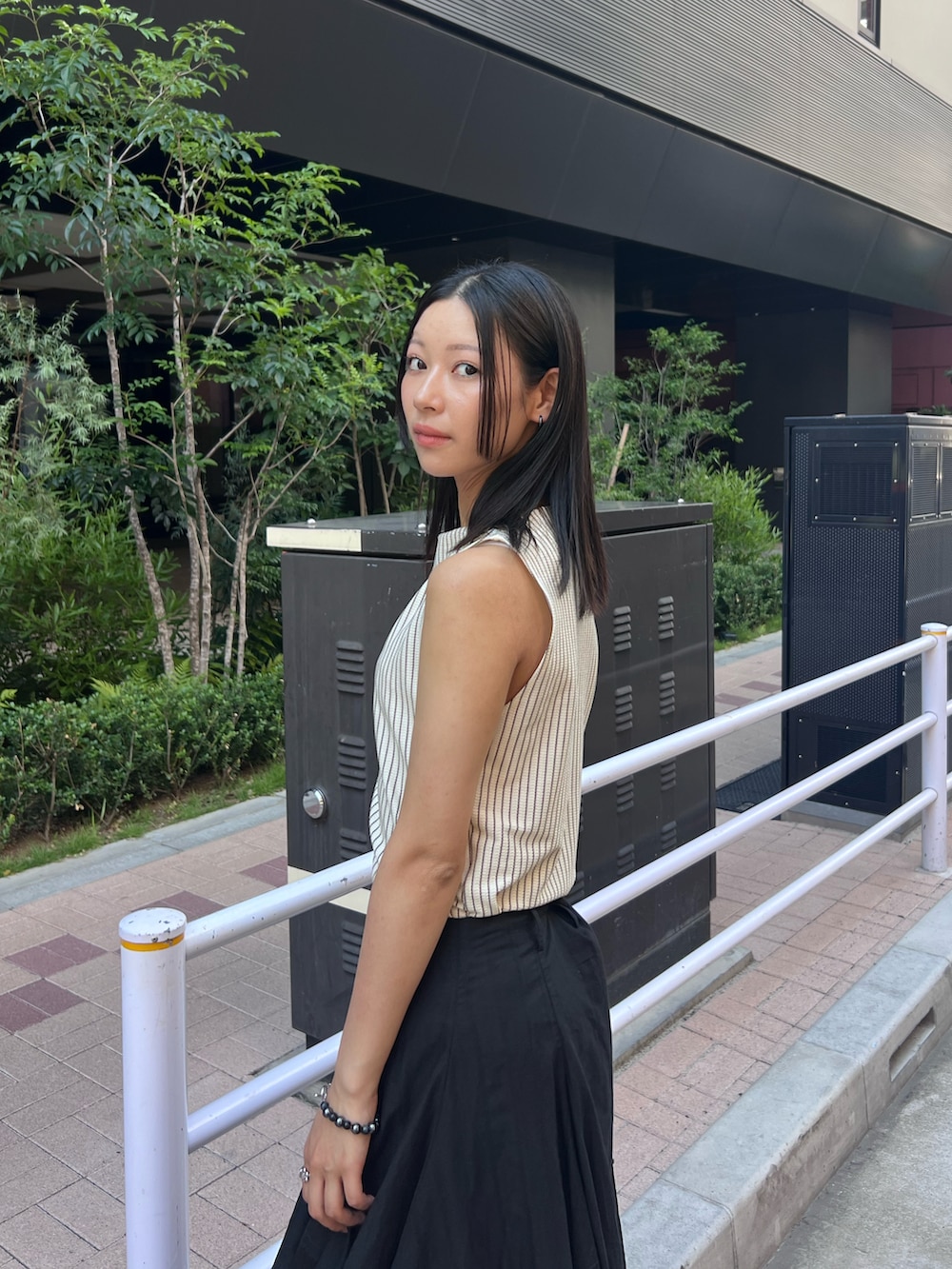 ブラック系のスカート、グレー系のTシャツ/カットソーを着用したレディースの夏コーディネートの2枚目の写真