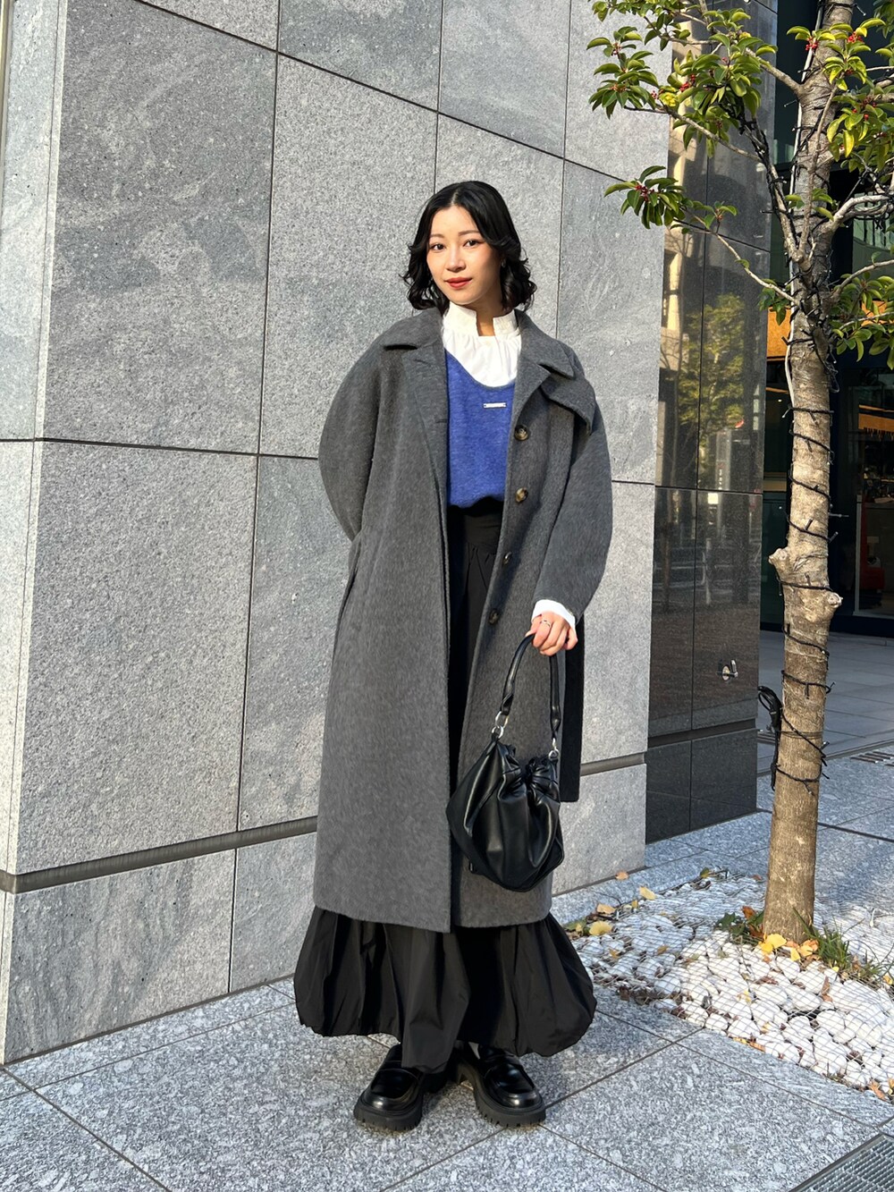 ブルー系のカーディガン/ボレロ、ブラック系のスカート、ブラック系のショルダーバッグを着用したレディースの春コーディネートの2枚目の写真