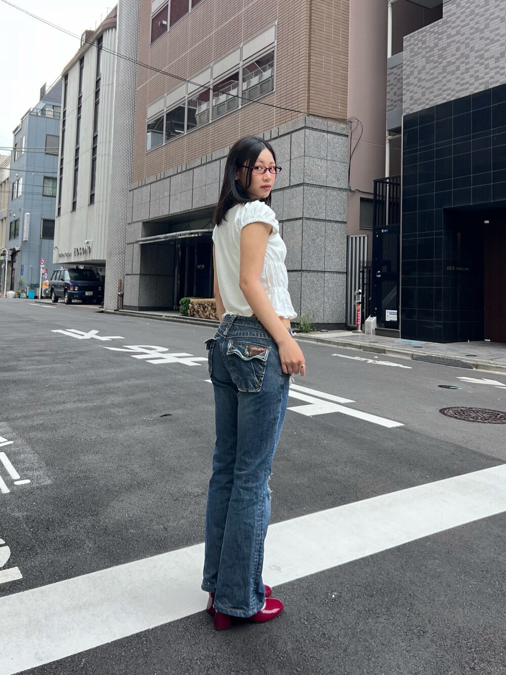 ホワイト系のTシャツ/カットソー、ブルー系のデニムパンツ、レッド系のシューズを着用したレディースの夏コーディネートの2枚目の写真