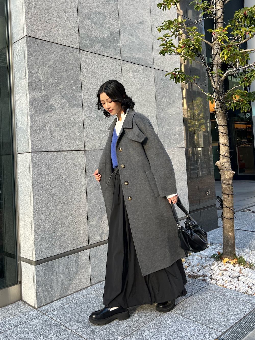 ブルー系のカーディガン/ボレロ、ブラック系のスカート、ブラック系のショルダーバッグを着用したレディースの春コーディネートの3枚目の写真