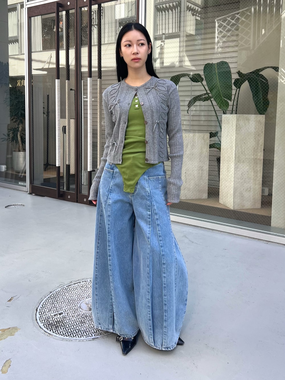グレー系のカーディガン/ボレロ、グリーン系のキャミソール、ブルー系のデニムパンツを着用したレディースの春コーディネートの5枚目の写真