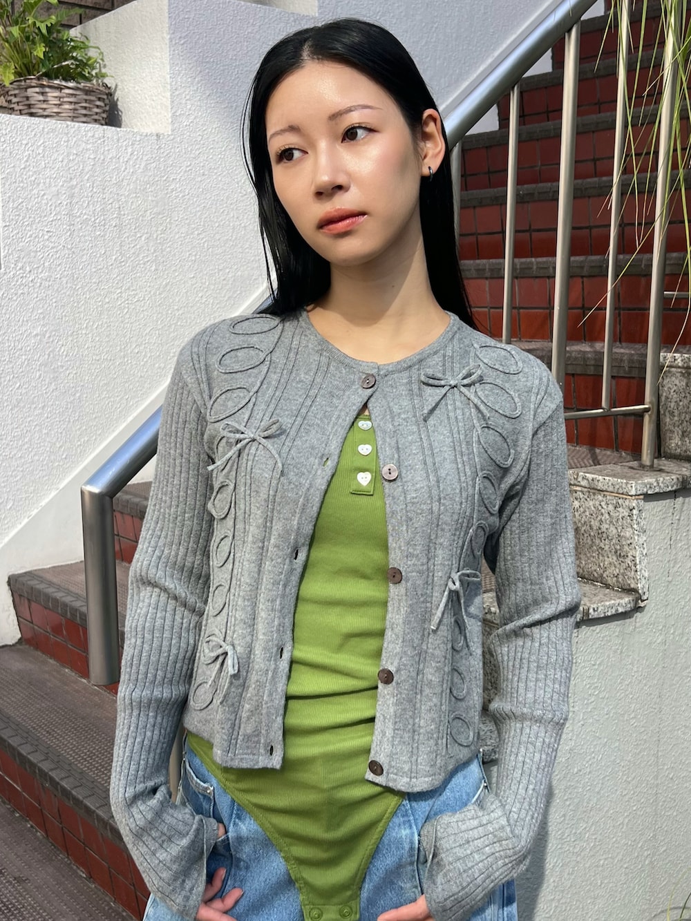 グレー系のカーディガン/ボレロ、グリーン系のキャミソール、ブルー系のデニムパンツを着用したレディースの春コーディネートの4枚目の写真