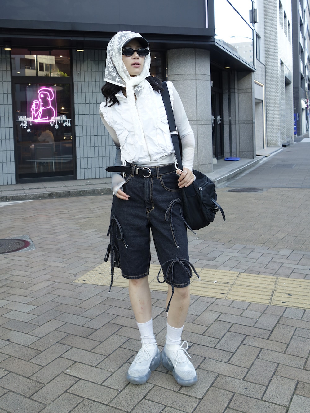 ホワイト系のベスト、ブラック系のデニムパンツ、ホワイト系のスニーカーを着用したレディースの夏コーディネートの2枚目の写真