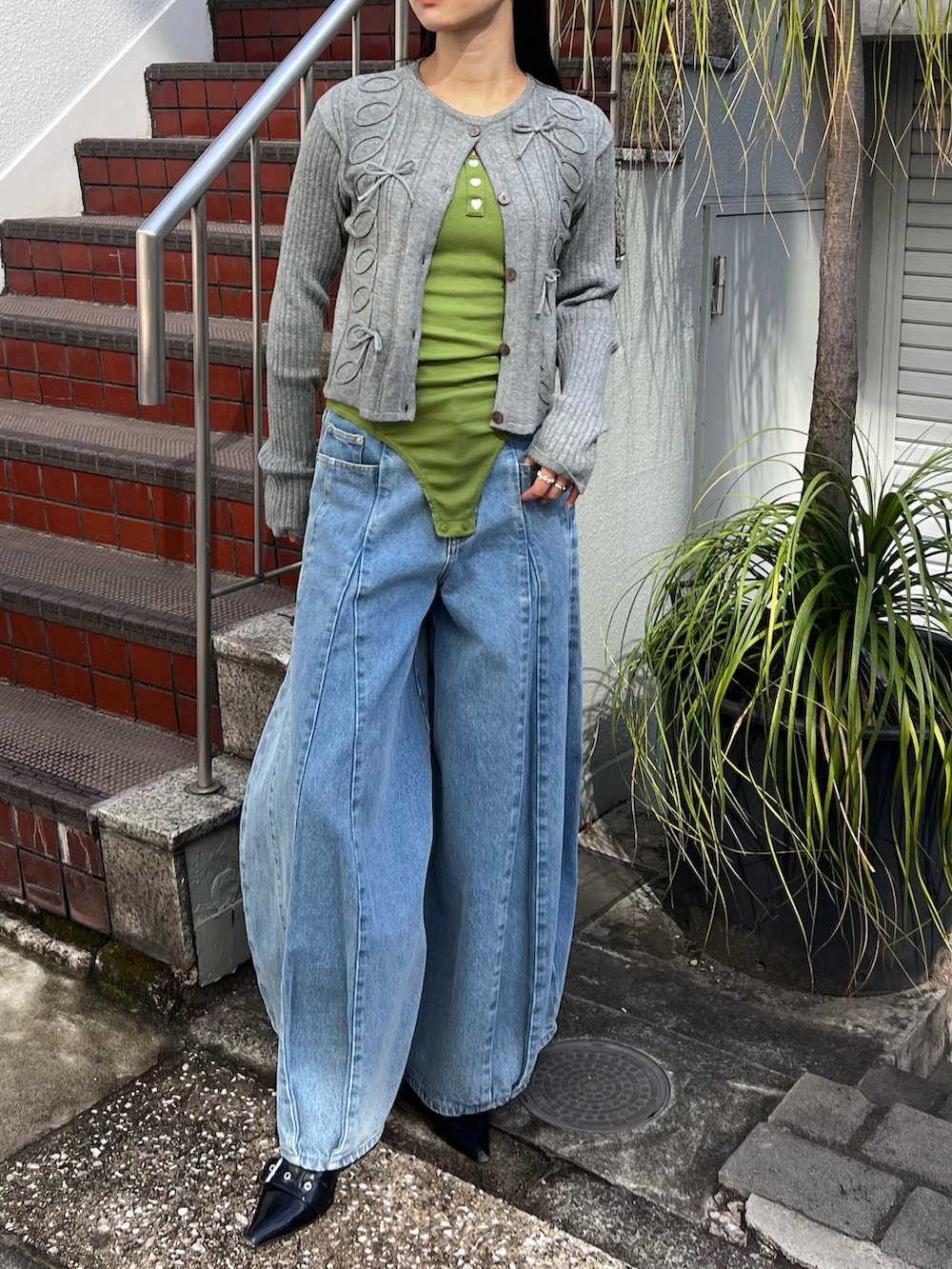 グレー系のカーディガン/ボレロ、グリーン系のキャミソール、ブルー系のデニムパンツを着用したレディースの春コーディネートの2枚目の写真