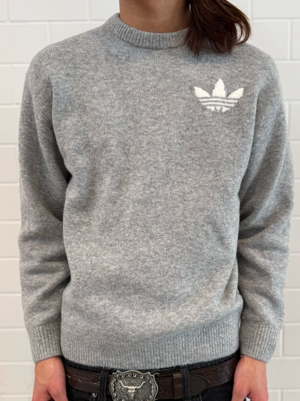 グレー系のニット/セーター、ブラック系のデニムパンツ、ホワイト系のスニーカーを着用したメンズの冬コーディネートの4枚目の写真