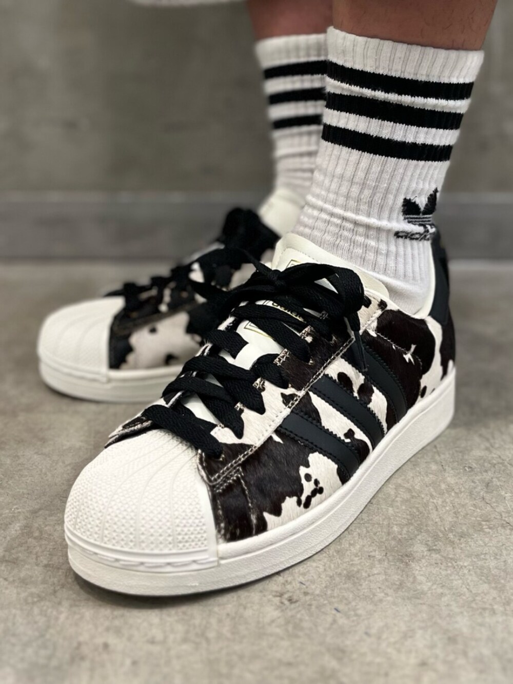 ブラック系のスニーカー、ホワイト系のナイロンジャケットを着用したメンズの夏コーディネートの4枚目の写真