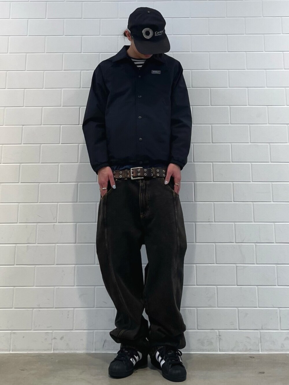 ブラック系のスニーカー、ブラック系のブルゾン、ブラウン系のデニムパンツを着用したメンズの冬コーディネートの3枚目の写真