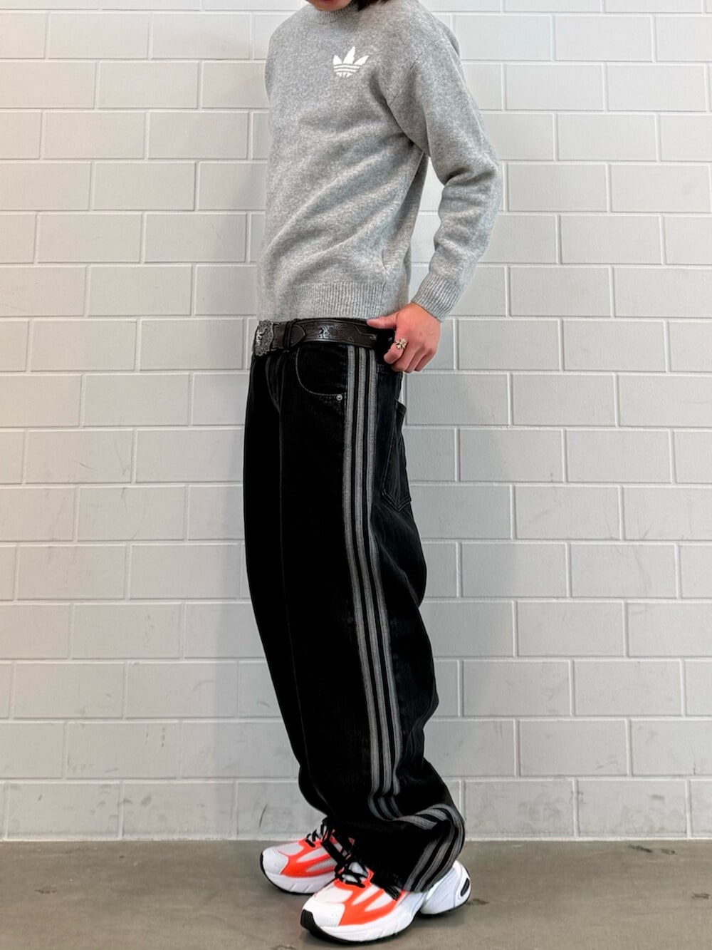 グレー系のニット/セーター、ブラック系のデニムパンツ、ホワイト系のスニーカーを着用したメンズの冬コーディネートの2枚目の写真
