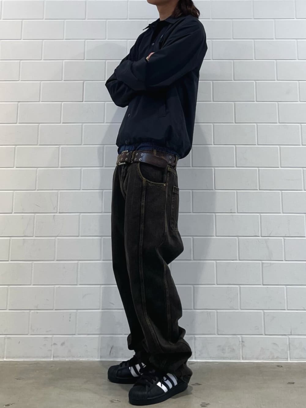 ブラック系のスニーカー、ブラック系のブルゾン、ブラウン系のデニムパンツを着用したメンズの冬コーディネートの2枚目の写真