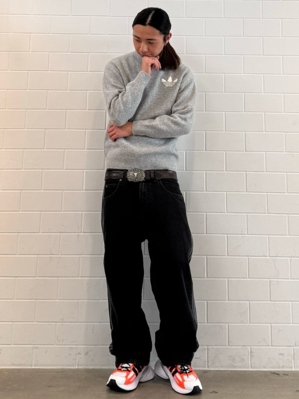 グレー系のニット/セーター、ブラック系のデニムパンツ、ホワイト系のスニーカーを着用したメンズの冬コーディネートの3枚目の写真