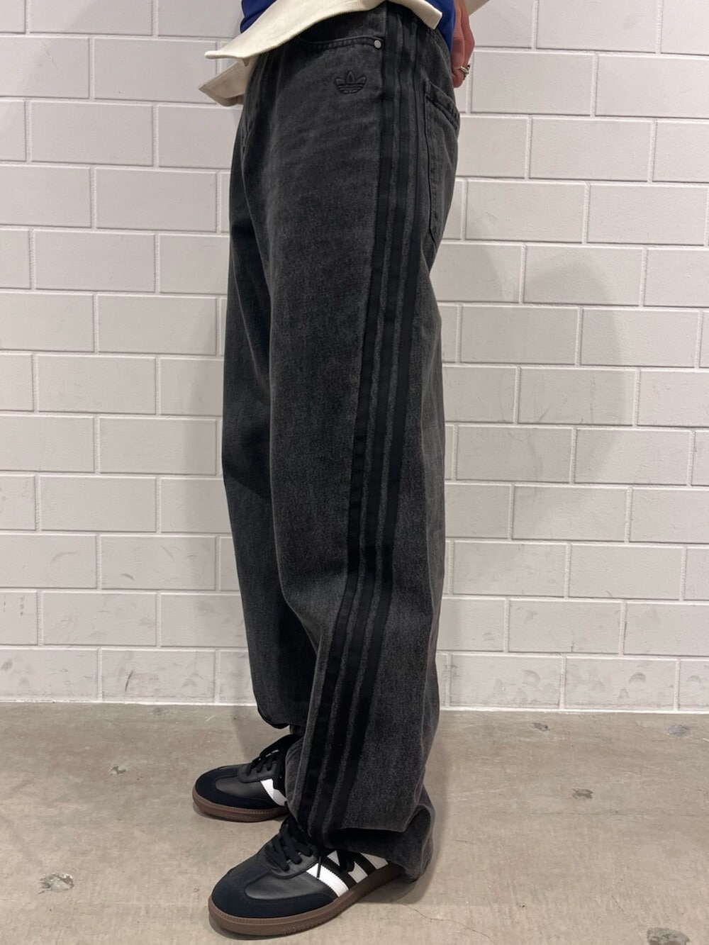 ブラック系のデニムパンツ、ブルー系のTシャツ/カットソー、ブラック系のスニーカーを着用したメンズの秋コーディネートの5枚目の写真