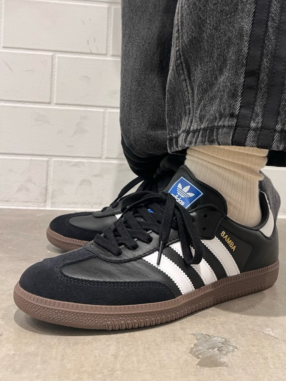 ブラック系のデニムパンツ、ブルー系のTシャツ/カットソー、ブラック系のスニーカーを着用したメンズの秋コーディネートの6枚目の写真