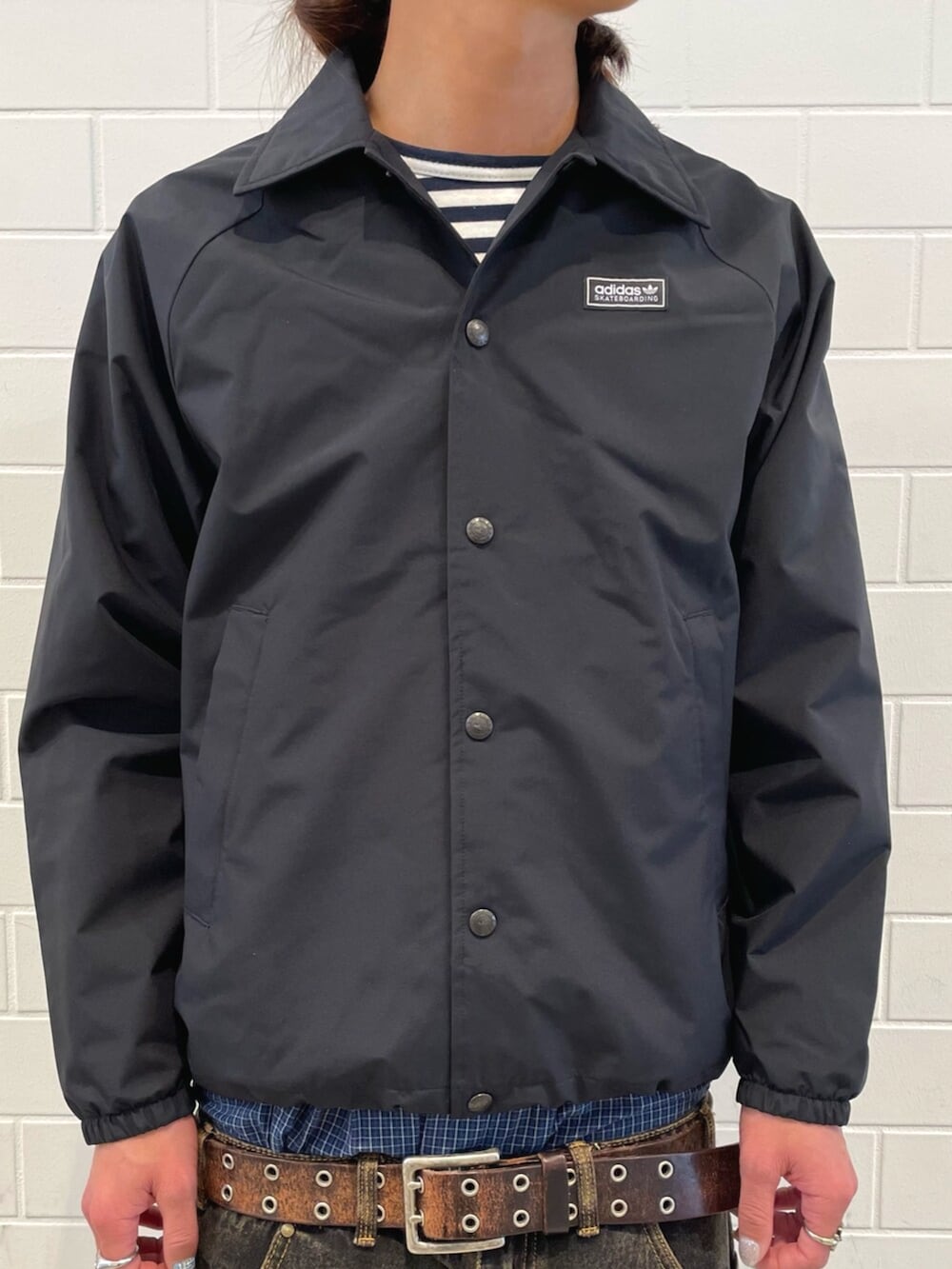 ブラック系のスニーカー、ブラック系のブルゾン、ブラウン系のデニムパンツを着用したメンズの冬コーディネートの4枚目の写真