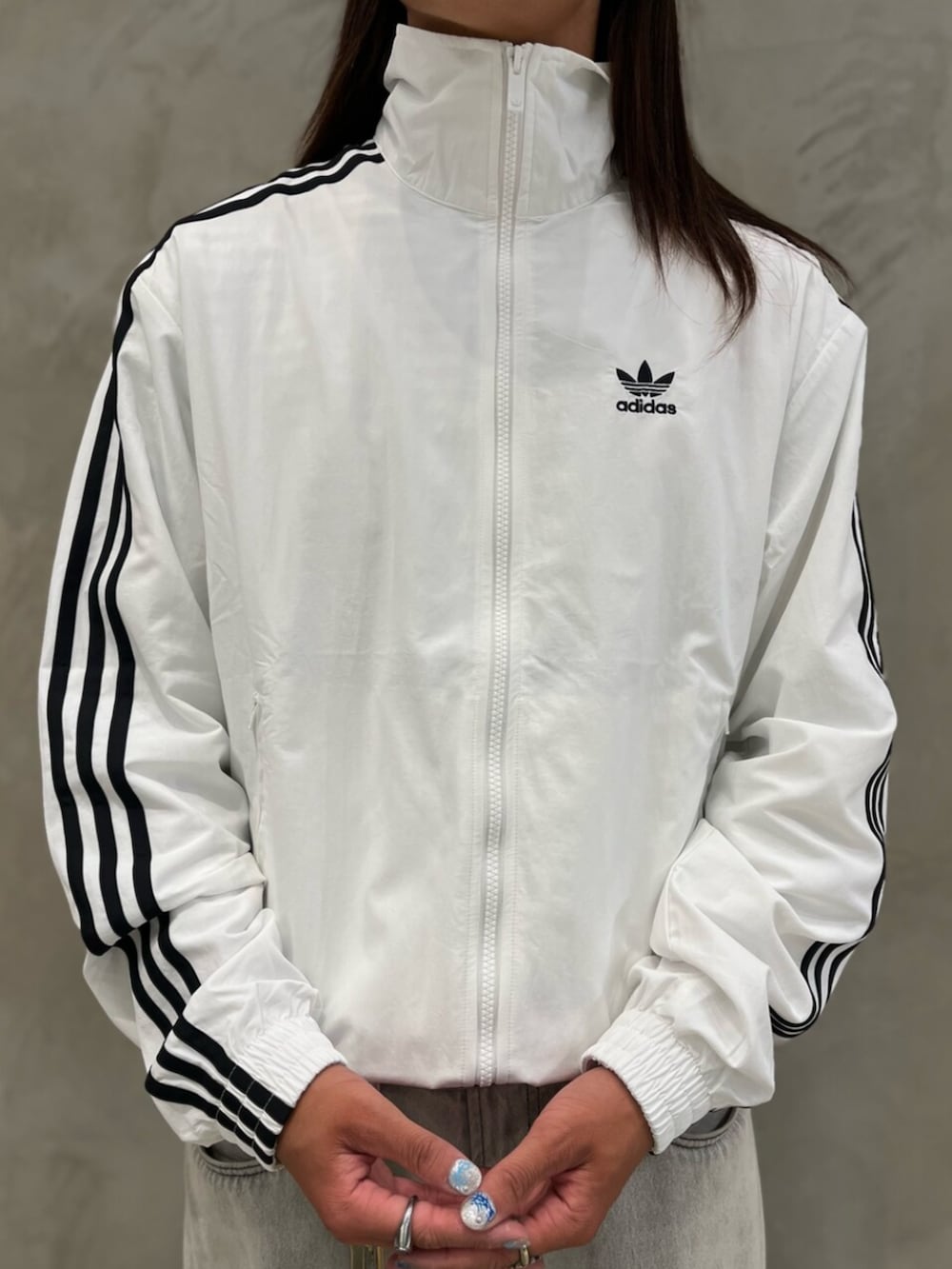 ブラック系のスニーカー、ホワイト系のナイロンジャケットを着用したメンズの夏コーディネートの3枚目の写真