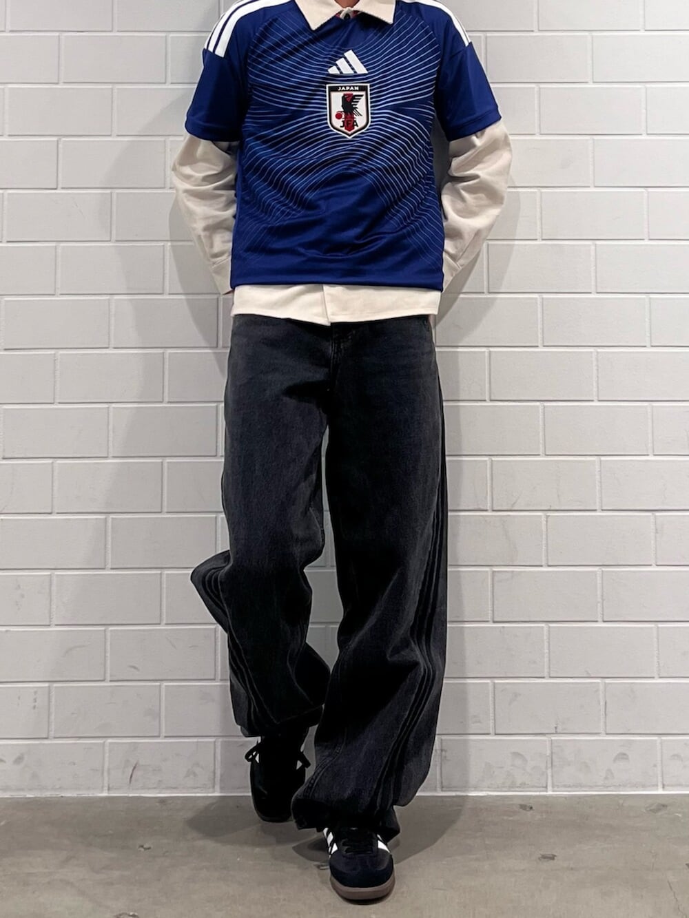 ブラック系のデニムパンツ、ブルー系のTシャツ/カットソー、ブラック系のスニーカーを着用したメンズの秋コーディネートの2枚目の写真