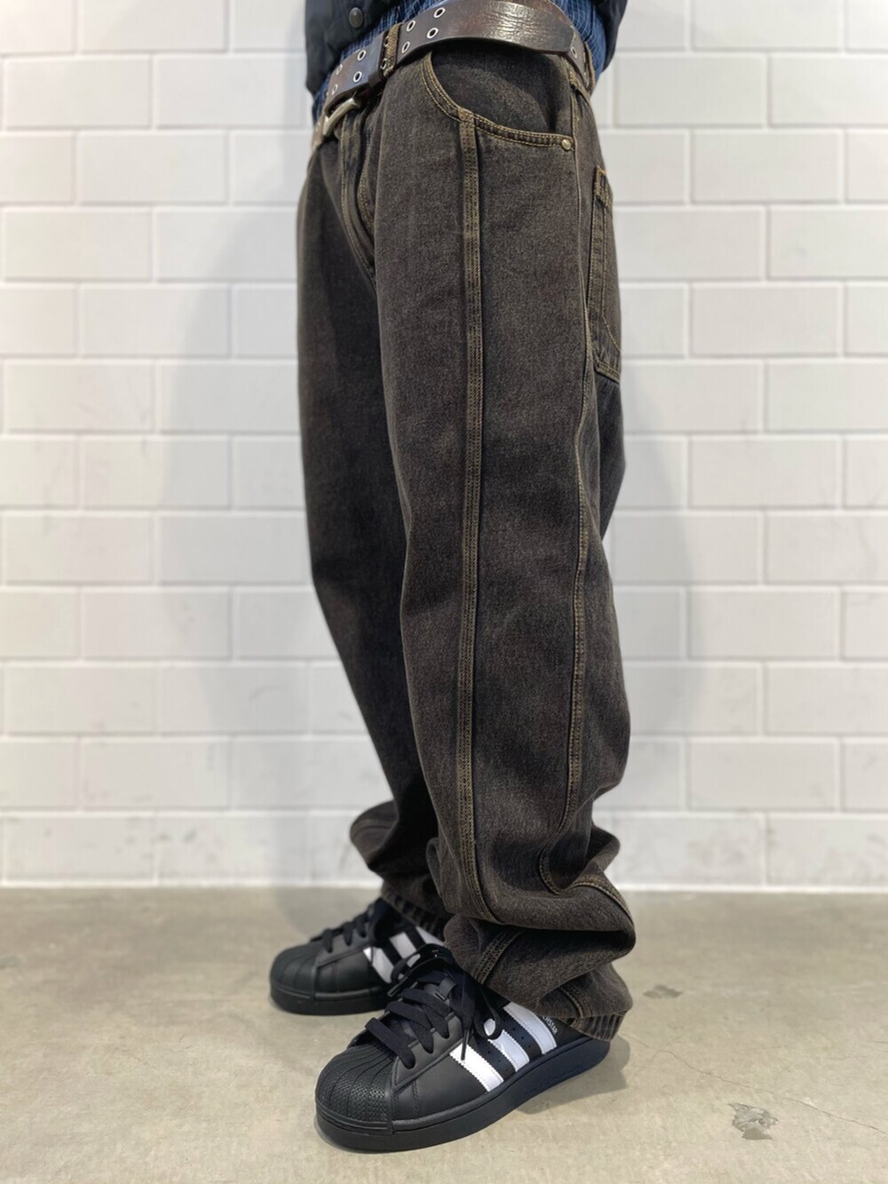 ブラック系のスニーカー、ブラック系のブルゾン、ブラウン系のデニムパンツを着用したメンズの冬コーディネートの5枚目の写真