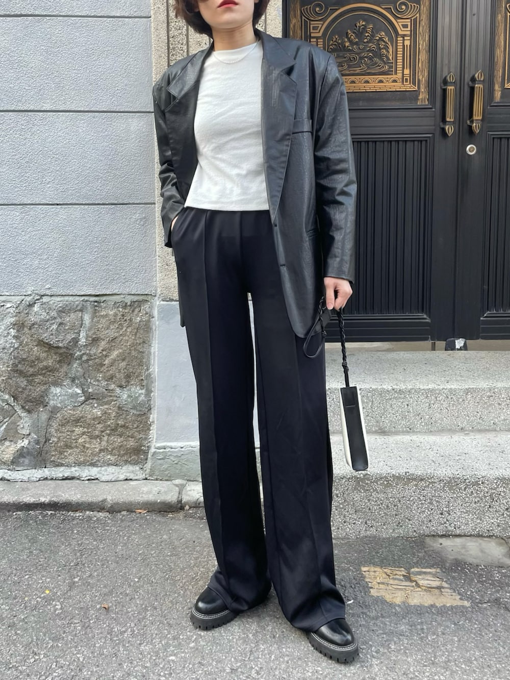 ブラック系のテーラードジャケット、ホワイト系のショルダーバッグ、ブラック系のスウェットパンツを着用したレディースの冬コーディネートの2枚目の写真