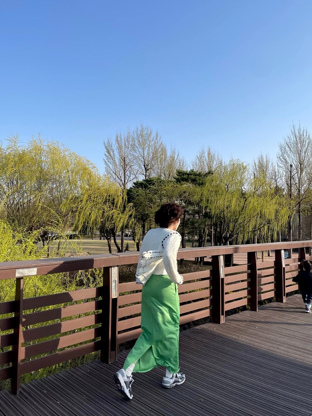 グリーン系のスカートを着用したレディースの春コーディネートの3枚目の写真