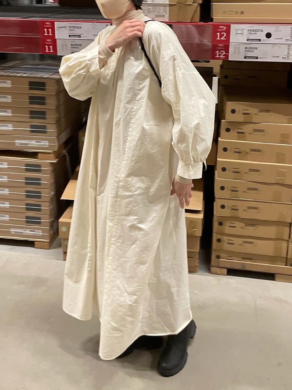 ベージュ系のワンピース、ブラック系のブーツ、ホワイト系のショルダーバッグを着用したレディースの冬コーディネートの3枚目の写真