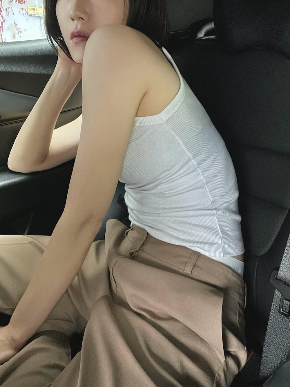 ホワイト系のキャミソール、ベージュ系のスラックス、ベージュ系のサンダルを着用したレディースの夏コーディネートの2枚目の写真