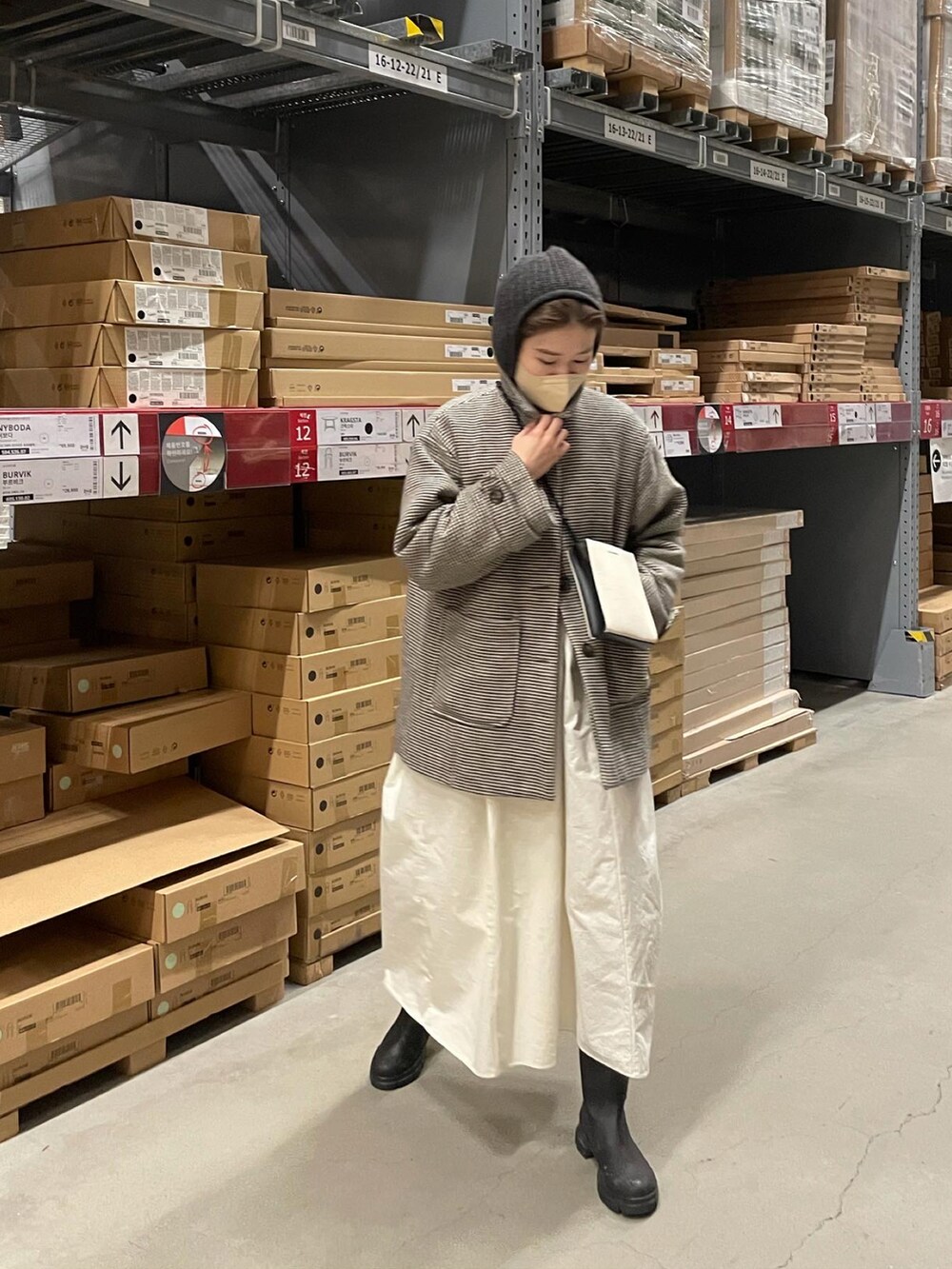 ベージュ系のワンピース、ブラック系のブーツ、ホワイト系のショルダーバッグを着用したレディースの冬コーディネートの2枚目の写真