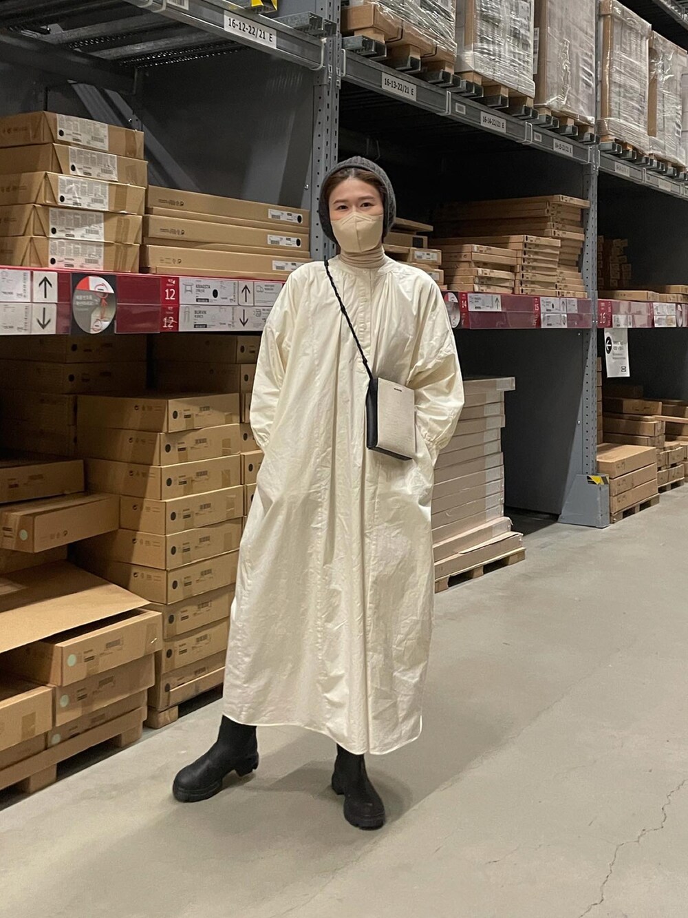 ベージュ系のワンピース、ブラック系のブーツ、ホワイト系のショルダーバッグを着用したレディースの冬コーディネートの4枚目の写真