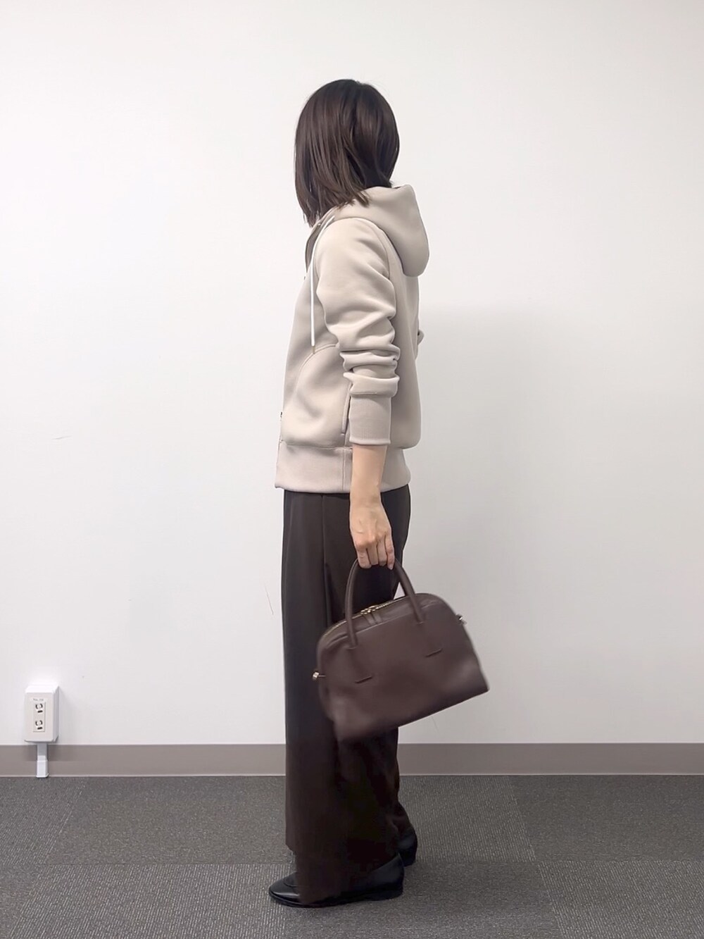 ベージュ系のパーカー、ブラウン系のスラックス、ブラウン系のボストンバッグを着用したレディースの秋コーディネートの3枚目の写真