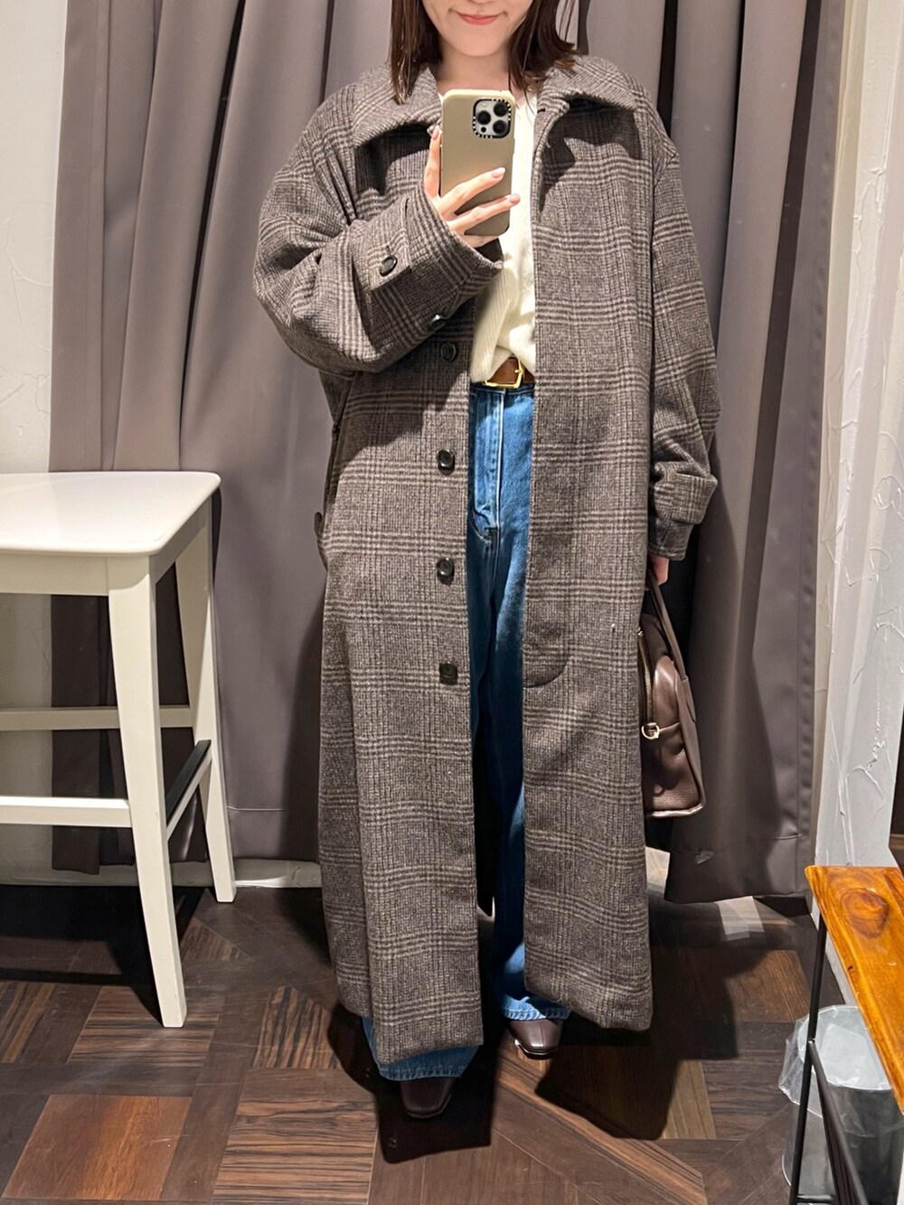 ブラウン系のステンカラーコート、ベージュ系のニット/セーター、ブラウン系のボストンバッグを着用したレディースの秋コーディネートの5枚目の写真