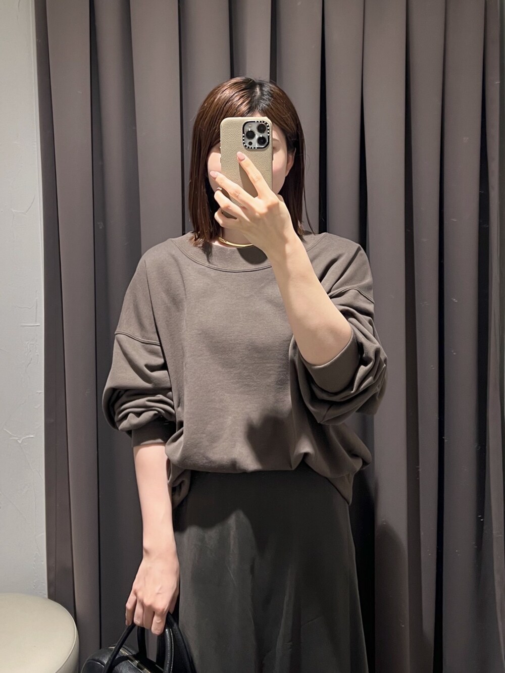 ブラウン系のスカート、ブラック系のボストンバッグ、ブラック系のパンプスを着用したレディースの冬コーディネートの4枚目の写真