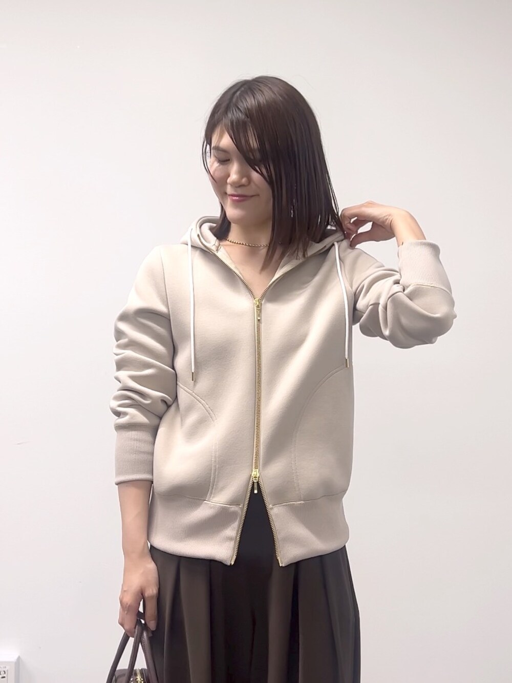 ベージュ系のパーカー、ブラウン系のスラックス、ブラウン系のボストンバッグを着用したレディースの秋コーディネートの5枚目の写真