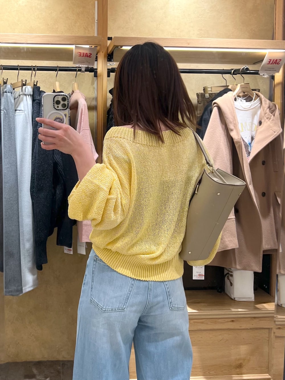 イエロー系のニット/セーター、ブルー系のデニムパンツを着用したレディースの冬コーディネートの5枚目の写真