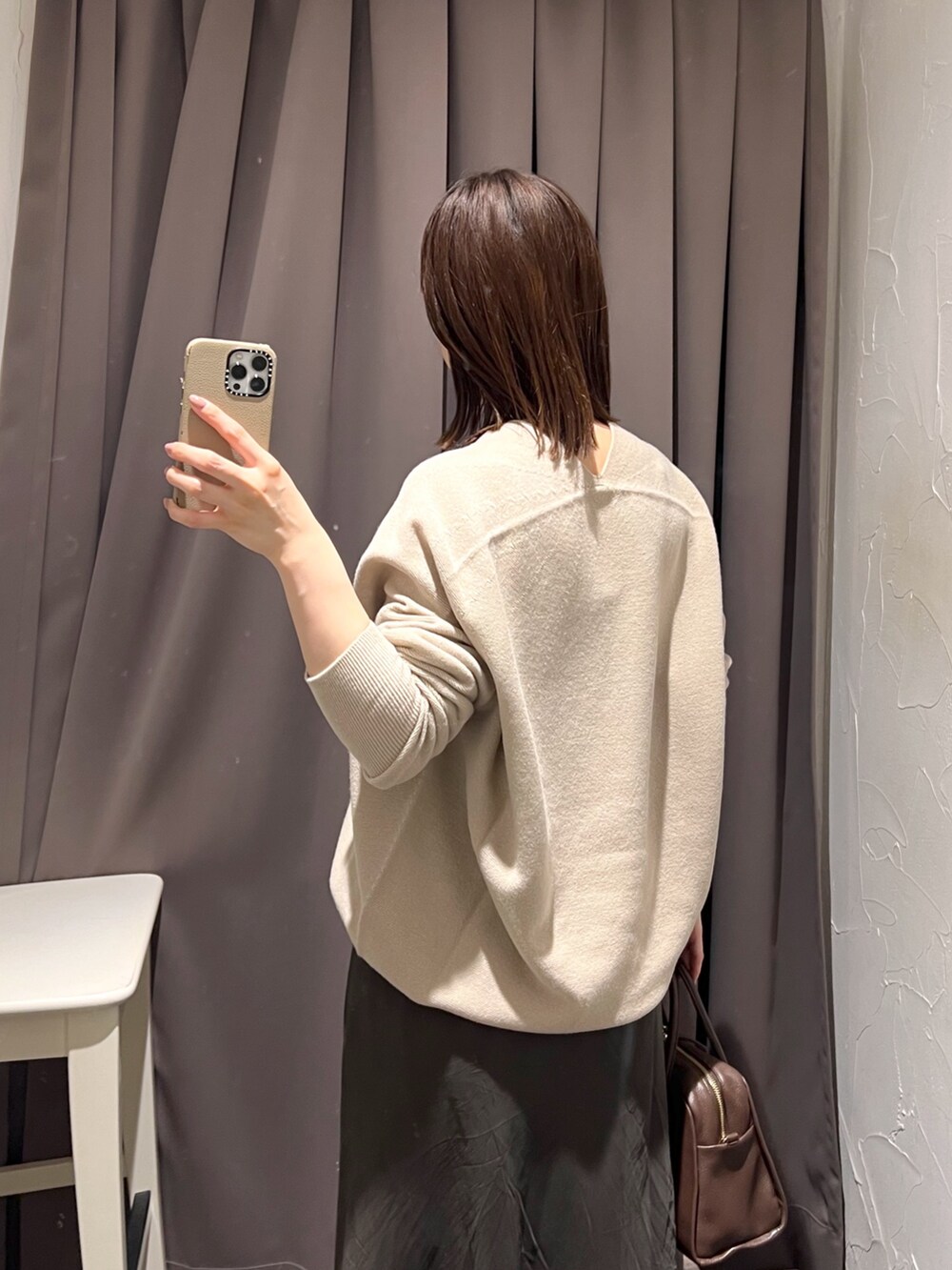 ベージュ系のニット/セーター、ブラウン系のスカート、ブラウン系のボストンバッグを着用したレディースの秋コーディネートの7枚目の写真