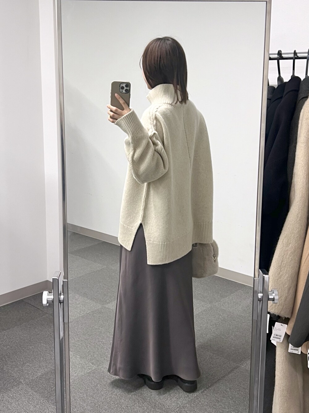 ベージュ系のボストンバッグ、ホワイト系のニット/セーター、ブラウン系のスカートを着用したレディースの秋コーディネートの3枚目の写真