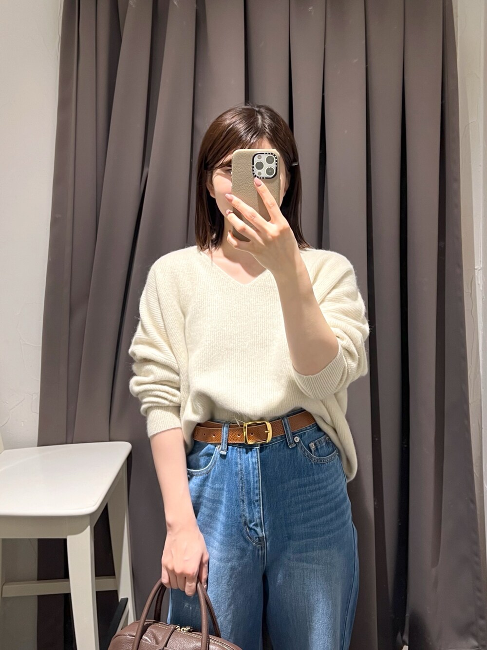 ベージュ系のニット/セーター、ブルー系のデニムパンツ、ブラウン系のボストンバッグを着用したレディースの秋コーディネートの5枚目の写真