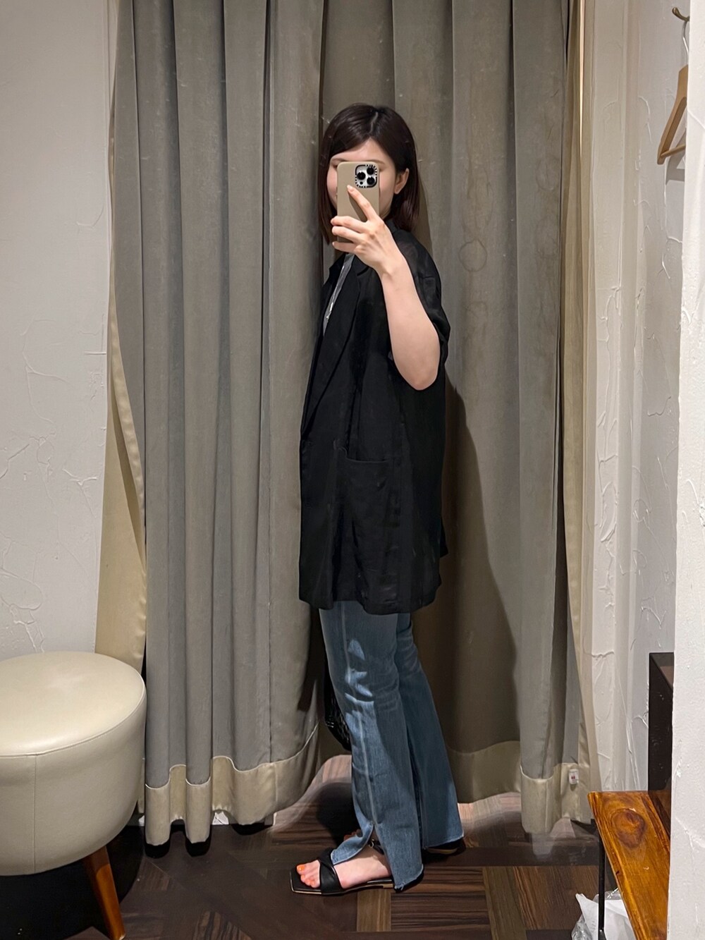 ブラック系のテーラードジャケット、ブルー系のデニムパンツ、ブラック系のサンダルを着用したレディースの夏コーディネートの2枚目の写真