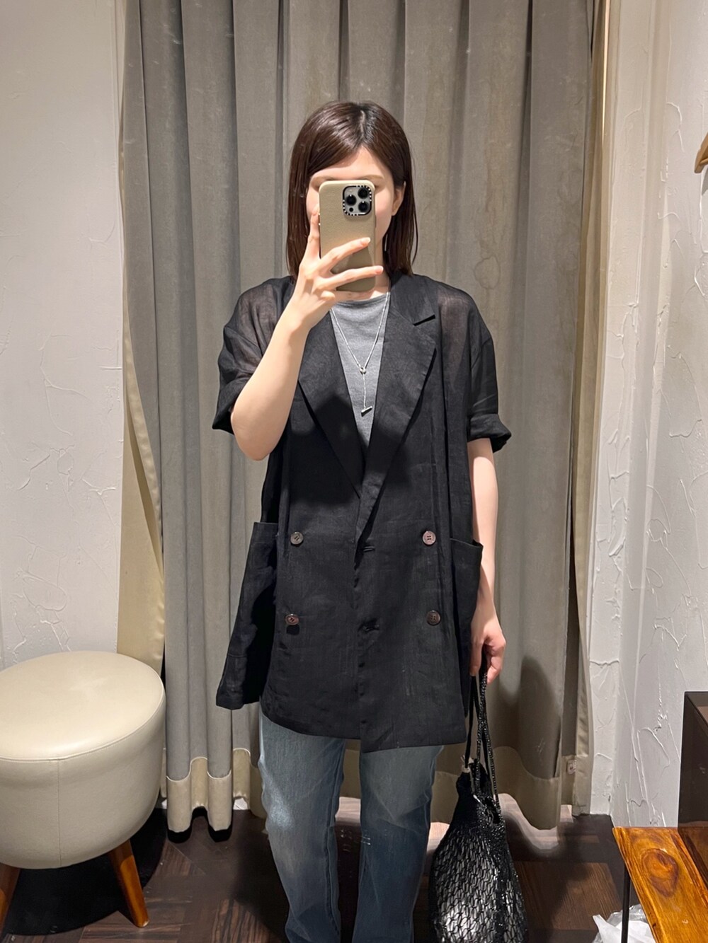 ブラック系のテーラードジャケット、ブルー系のデニムパンツ、ブラック系のサンダルを着用したレディースの夏コーディネートの4枚目の写真