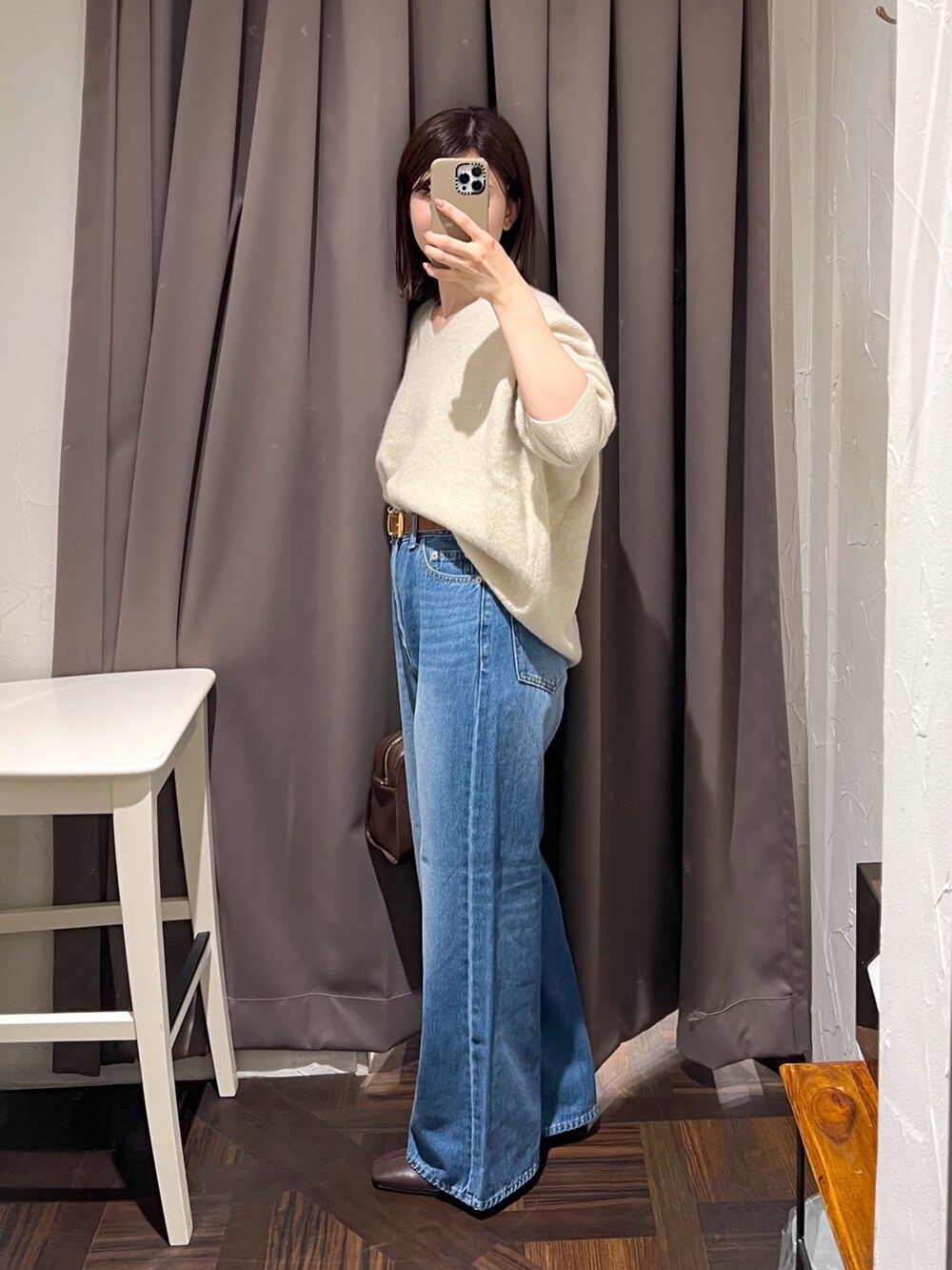 ベージュ系のニット/セーター、ブルー系のデニムパンツ、ブラウン系のボストンバッグを着用したレディースの秋コーディネートの3枚目の写真