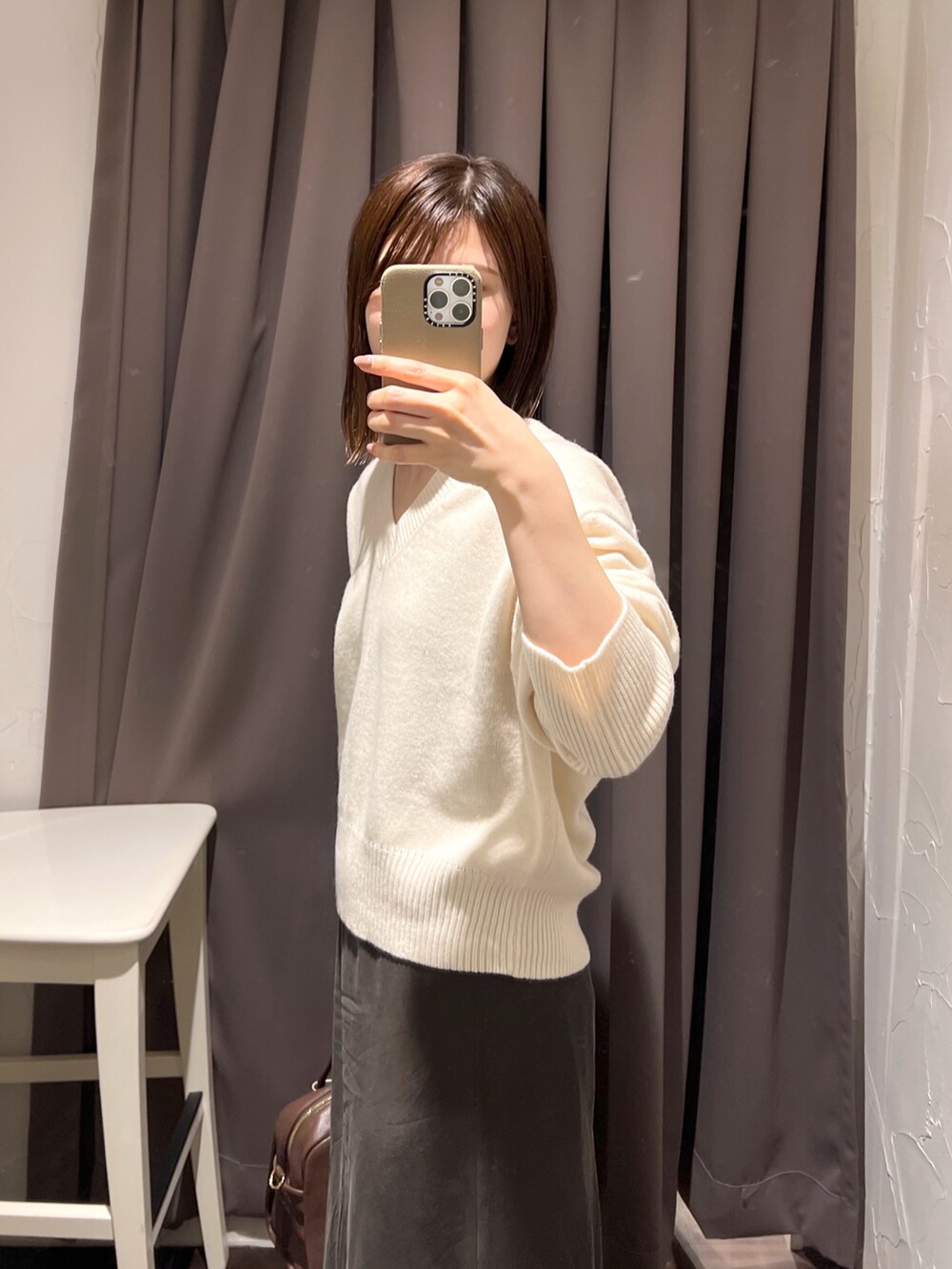 ホワイト系のニット/セーター、ブラウン系のボストンバッグ、ブラウン系のスカートを着用したレディースの秋コーディネートの6枚目の写真