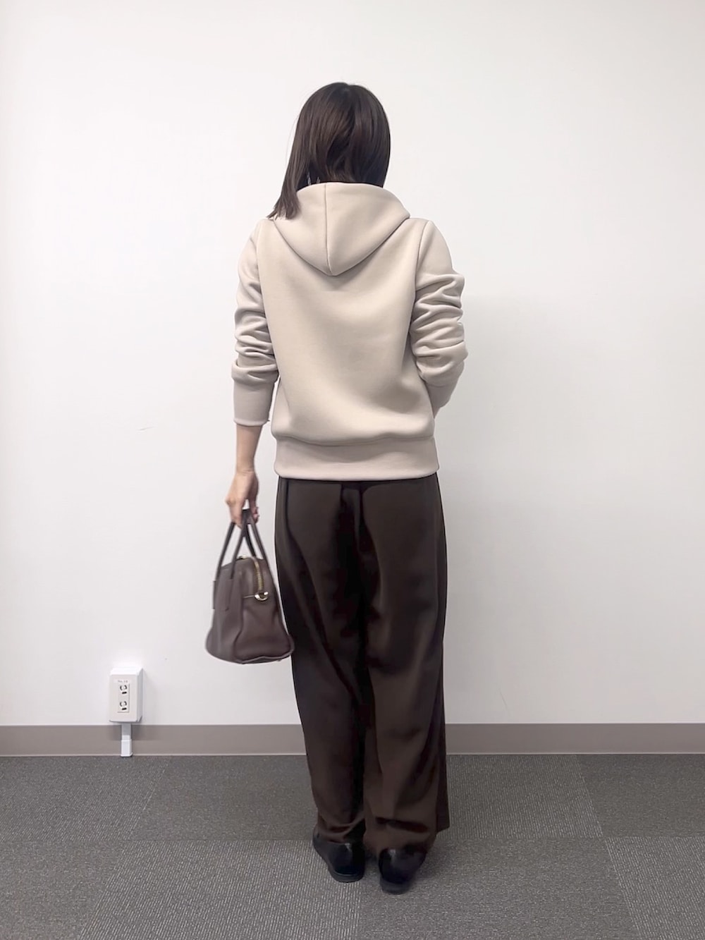 ベージュ系のパーカー、ブラウン系のスラックス、ブラウン系のボストンバッグを着用したレディースの秋コーディネートの4枚目の写真