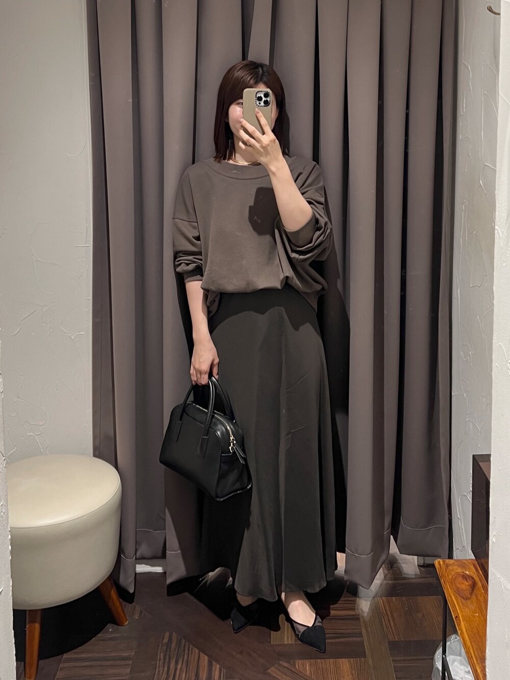 ブラウン系のスカート、ブラック系のボストンバッグ、ブラック系のパンプスを着用したレディースの冬コーディネートの2枚目の写真