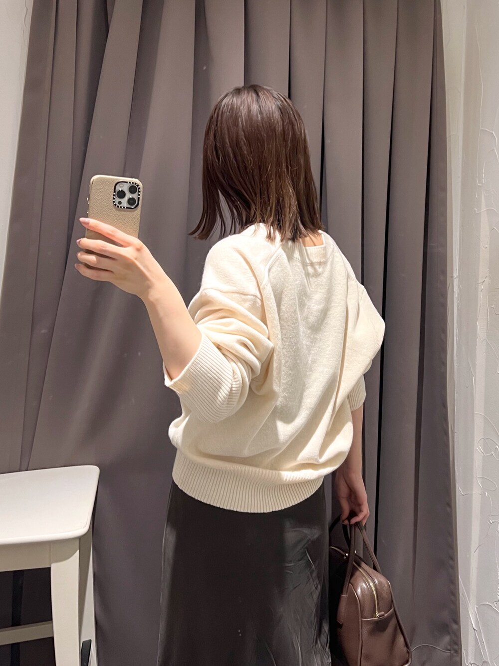 ホワイト系のニット/セーター、ブラウン系のボストンバッグ、ブラウン系のスカートを着用したレディースの秋コーディネートの7枚目の写真