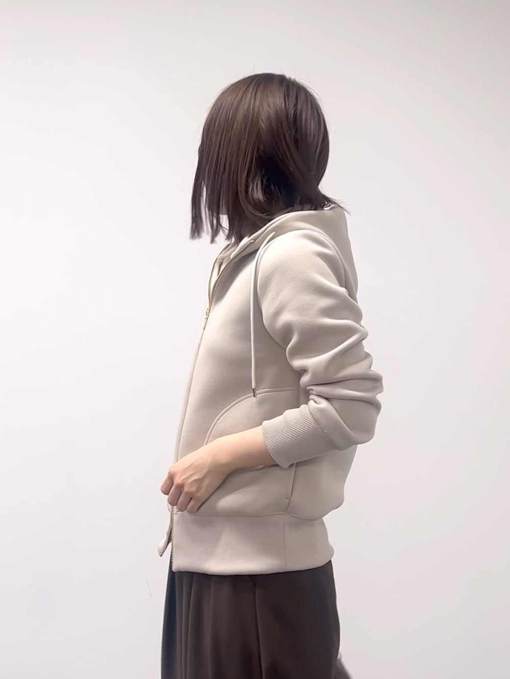 ベージュ系のパーカー、ブラウン系のスラックス、ブラウン系のボストンバッグを着用したレディースの秋コーディネートの6枚目の写真